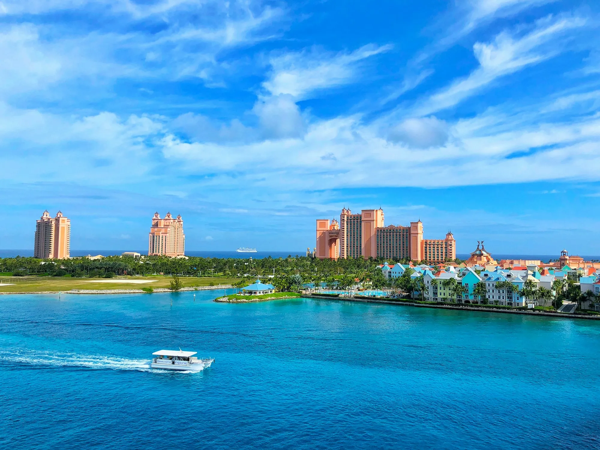 View across the turquoise harbour to Atlantis Paradise Island's pink towers, with a tour boat crossing the channel toward Nassau